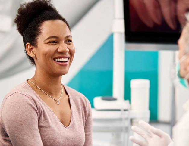 Woman smiling in modern dental office with turquoise and white decor in background.