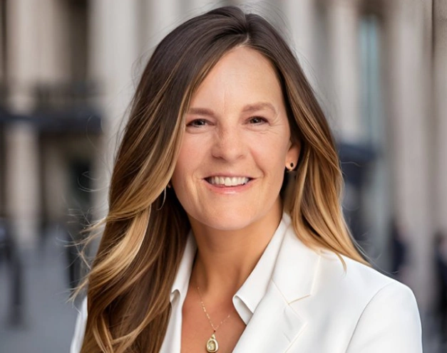 Professional woman in white blazer smiling outdoors, dental practice staff portrait