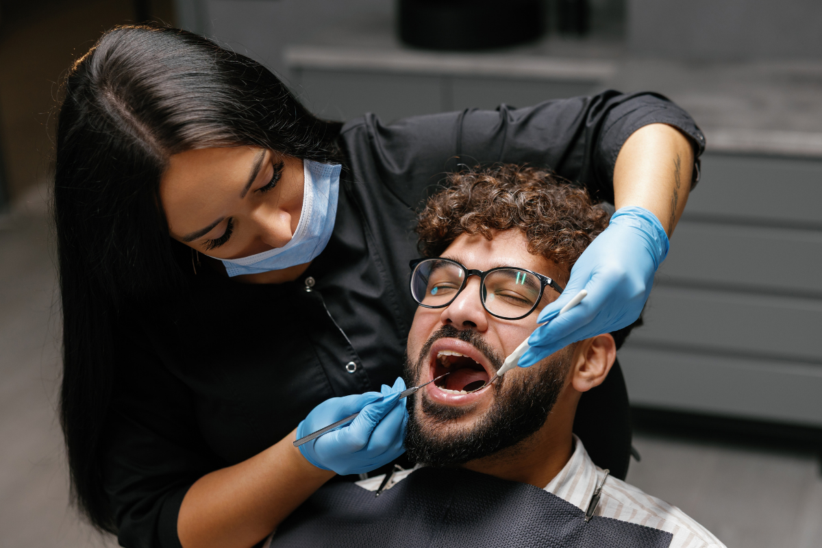 Female dentist examining male patient's teeth during dental checkup in Gonzales, LA.